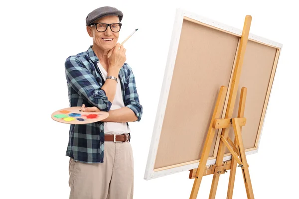 Artista sênior posando ao lado de uma tela — Fotografia de Stock