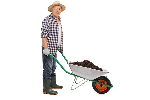 Trabajador empujando una carretilla llena de tierra — Foto de Stock