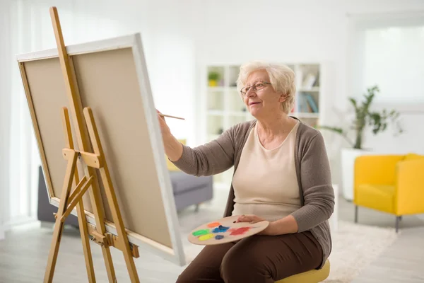 Mature lady painting on a canvas