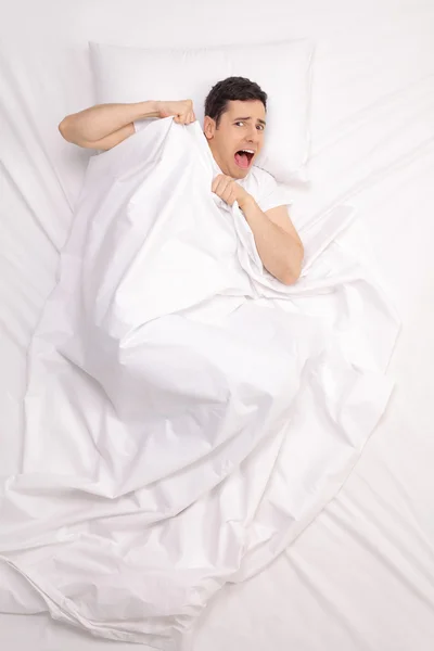 Joven asustado acostado en la cama — Foto de Stock