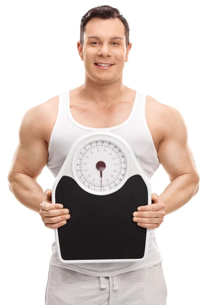 Muscular man holding a weight scale — Stock Photo, Image