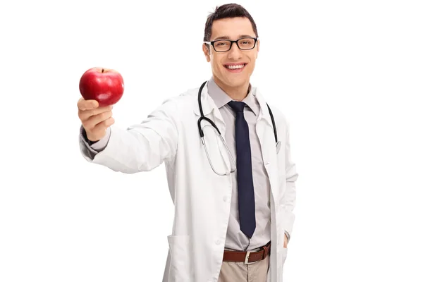 Cheerful young doctor holding an apple — Stock Photo, Image