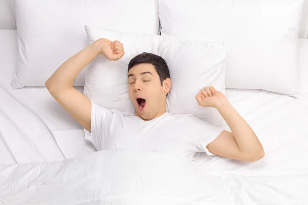 Rested man waking up in a bed — Stock Photo, Image