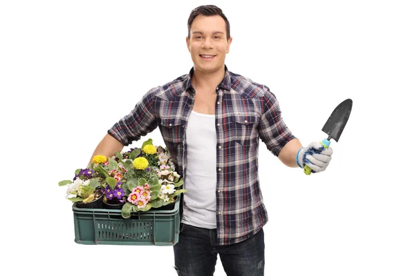 Man håller rack av blommor och spade — Stockfoto