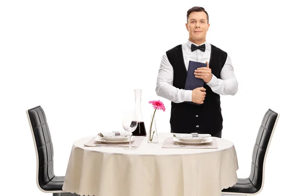 Waiter holding a menu next to a table — Stock Photo, Image