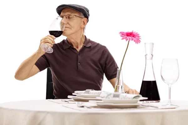 Старший джентльмен нюхает вино в ресторане — стоковое фото