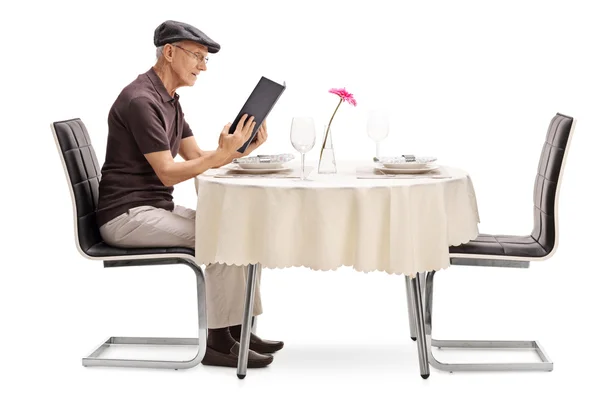 Senior man zit aan de tafel van een restaurant — Stockfoto