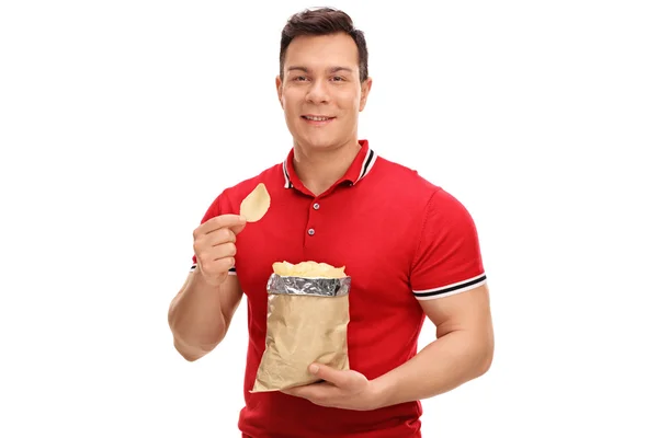 Junger Mann isst Kartoffelchips — Stockfoto