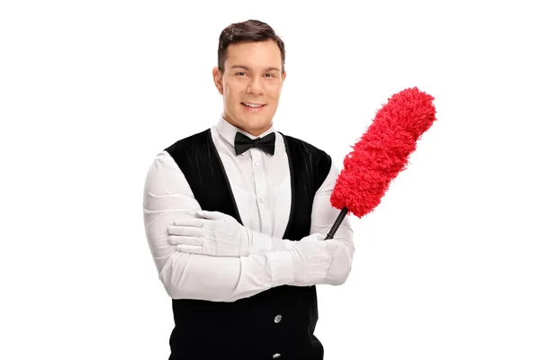 Young cheerful butler holding a duster — Stock Photo, Image