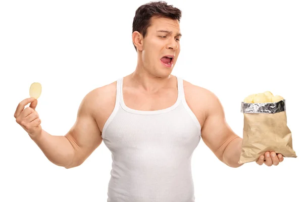 Displeased guy holding a bag of chips — Stock Photo, Image