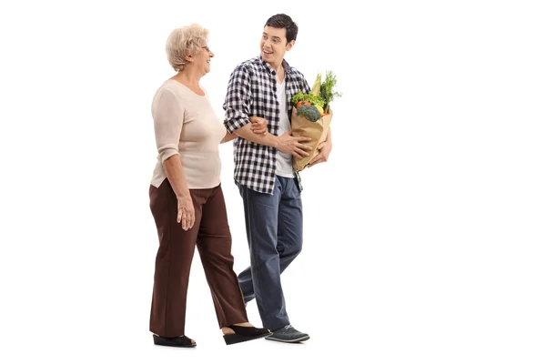 Man helping a senior lady with groceries — Stock Photo, Image