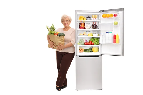 Senior lady leaning on a fridge — Stock Photo, Image