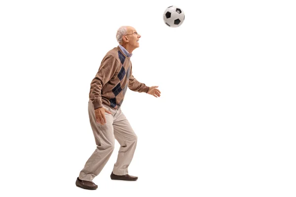 Senior homem dirigindo uma bola de futebol — Fotografia de Stock