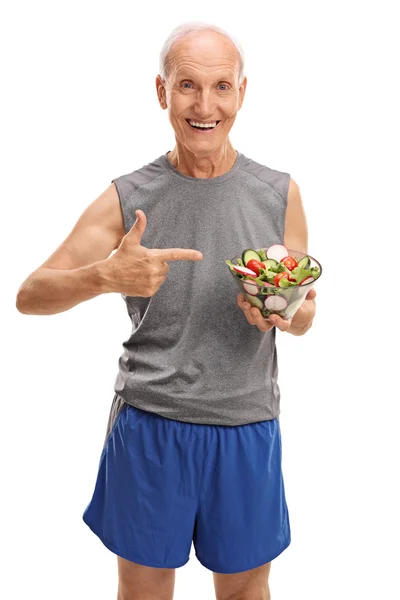 Hombre mayor en ropa deportiva sosteniendo una ensalada — Foto de Stock