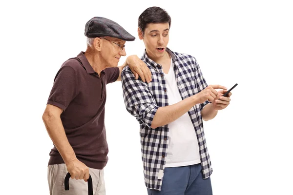 Хлопець показує щось на мобільному телефоні старшому чоловікові — стокове фото