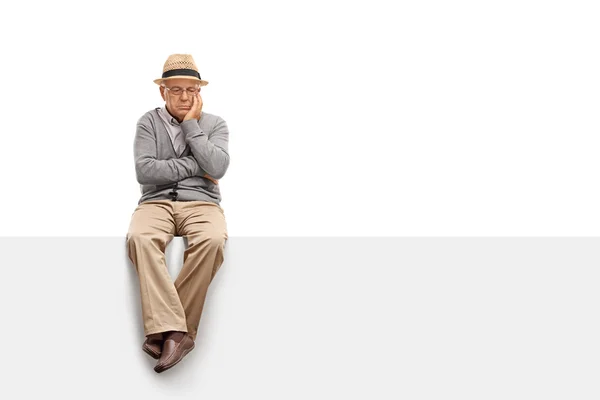 Depressed senior man sitting on a panel — Stock Photo, Image