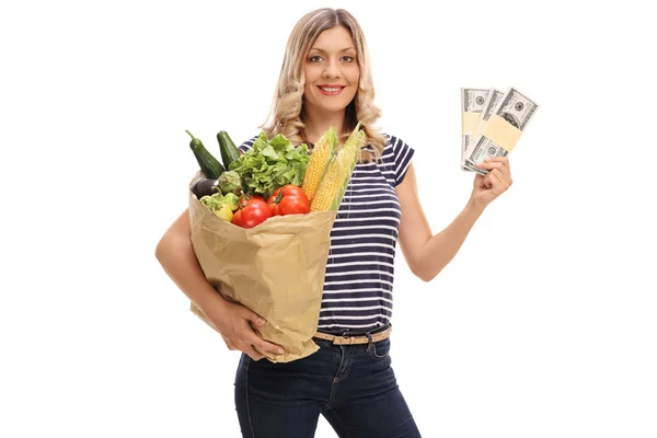 Mujer sosteniendo una bolsa de comestibles y dinero — Foto de Stock