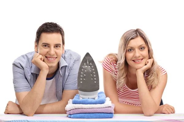 Couple posing by an iron and pile of clothes — Stock Photo, Image