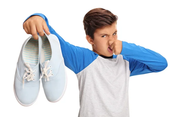 Menino segurando par de sapatos fedorentos — Fotografia de Stock