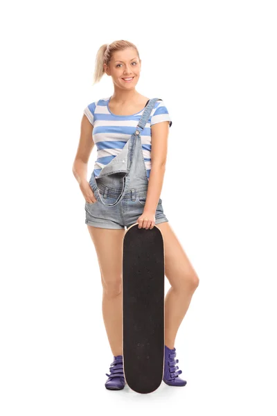 Хипстерская девушка позирует со скейтбордом — стоковое фото