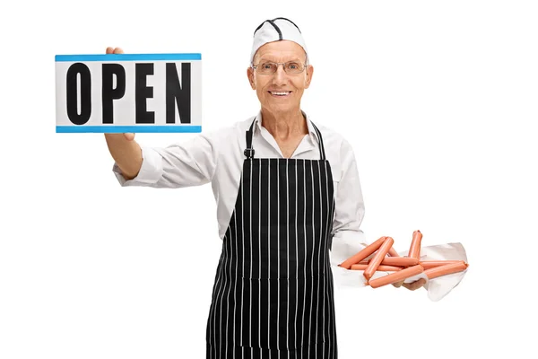 Butcher holding sausages and an open sign — Stock Photo, Image