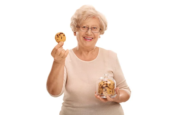 Mujer sosteniendo una galleta y un tarro de galletas — Foto de Stock