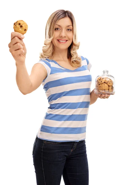 Mulher segurando um biscoito e um pote de biscoitos — Fotografia de Stock