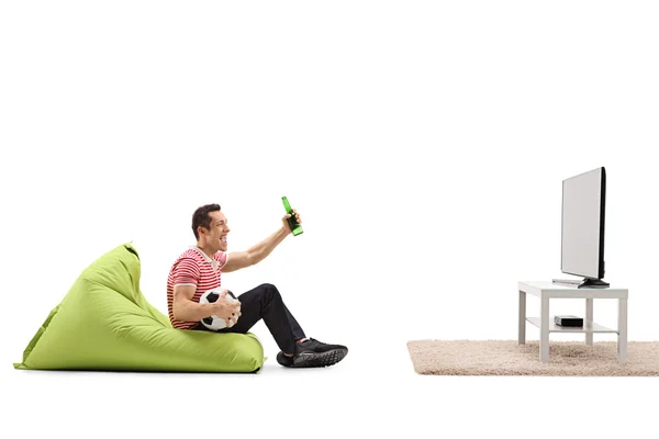 Chico sentado en una bolsa de frijoles viendo fútbol — Foto de Stock