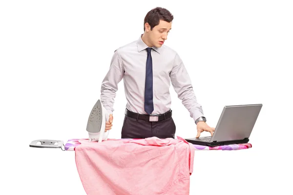 Man ironing and working on a laptop — Stock Photo, Image