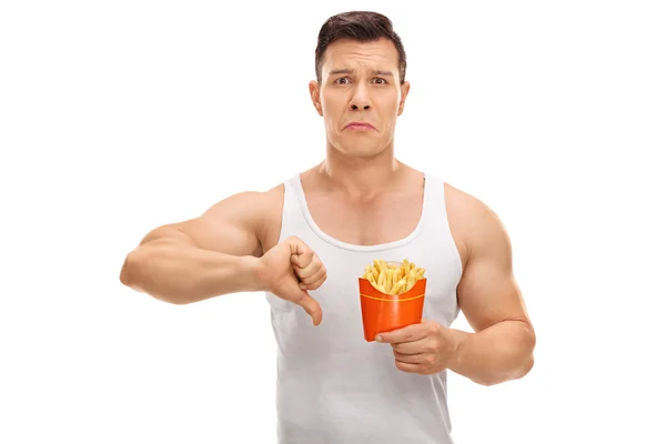 Hombre sosteniendo papas fritas y haciendo un pulgar hacia abajo signo — Foto de Stock