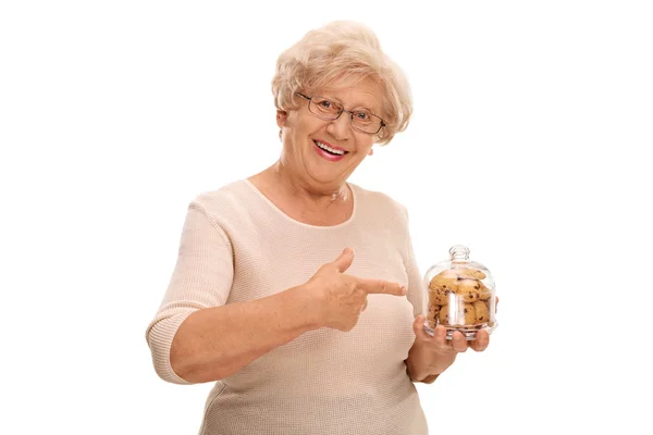 Kurabiye kavanozu tutarak ve işaret eden yaşlı kadın — Stok fotoğraf