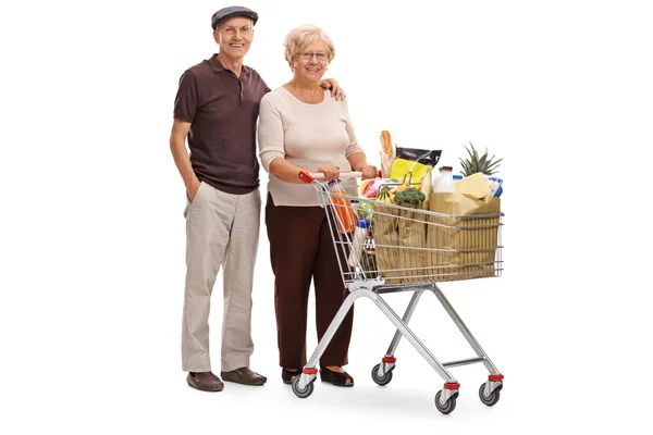 Elderly couple posing with a shopping cart — Stock Photo, Image