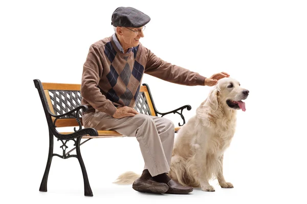 Mature man sitting on a bench and petting his dog — Stock Photo, Image