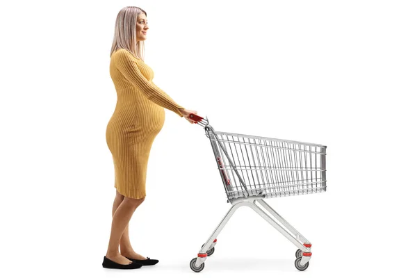 白い背景に隔離されたショッピングカートを押す妊婦の完全な長さのプロフィールショット — ストック写真