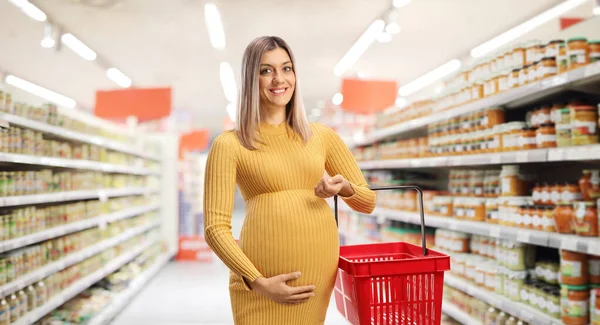 Uśmiechnięta Kobieta Ciąży Trzymająca Koszyk Zakupów Pozująca Supermarkecie — Zdjęcie stockowe
