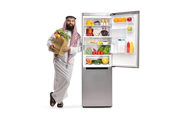 Араб Пакетом Продуктов Опирается Открытый Холодильник Полный Еды Изолированной Белом — стоковое фото