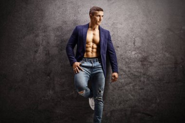 Paslı gri bir duvara yaslanan yakışıklı erkek model. 