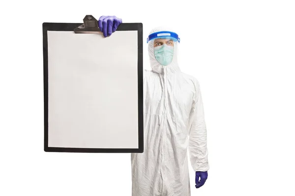 白い背景に隔離されたクリップボード上の空白の紙を示す顔の盾を持つハズマットのスーツの男 — ストック写真