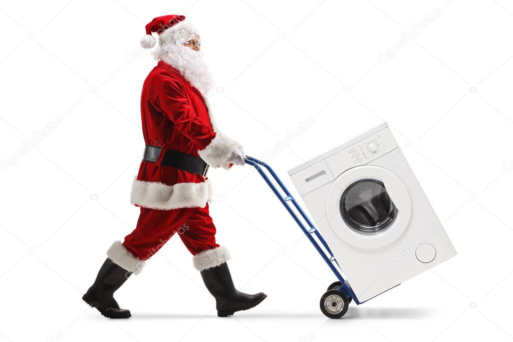 Full length portrait of a santa claus pushing a washing machine on a hand truck isolated on white background