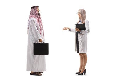 Beyaz arka planda, erkek bir Arap hastayla konuşan kadın bir doktorun tam boy profil çekimi.
