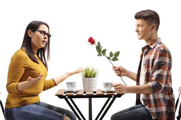 男人把玫瑰送给了一个愤怒的年轻女子 她在一家咖啡馆里被隔离在白人背景之外 — 图库照片