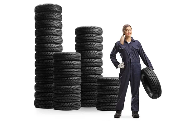 Female Auto Mechanic Holding Tire Standing Next Piles Tires Isolated — Stock Photo, Image