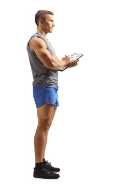 Beyaz arkaplana izole edilmiş bir belge yazan bir erkek fitness eğitmeninin tam boy profil çekimi