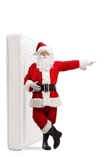 Full Length Portrait Santa Claus Leaning Bed Mattress Pointing Side — Stock Photo, Image