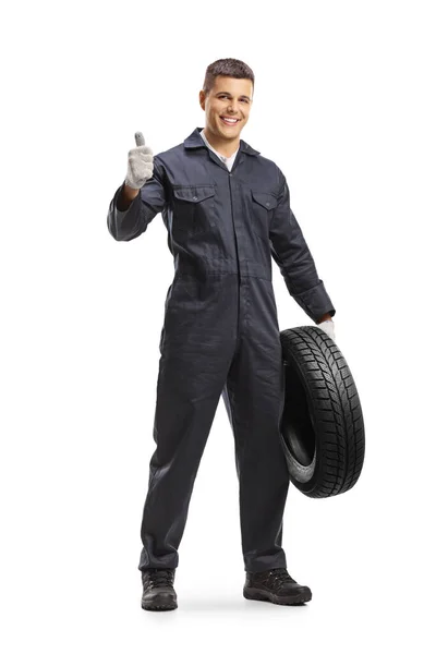兴高采烈的汽车修理工拿着车胎 把大拇指伸出来 与白色背景隔离 — 图库照片