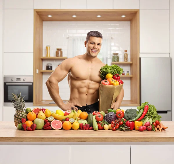 Homem Musculoso Topless Uma Cozinha Com Saco Papel Pilha Frutas — Fotografia de Stock