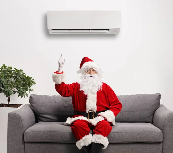 Santa Claus Sedí Pohovce Ukazuje Klimatizační Jednotku Nad Stěnou — Stock fotografie