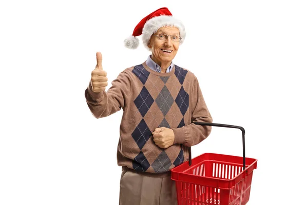 提着购物篮的老人竖起大拇指 戴着一顶白色背景的圣诞帽 — 图库照片