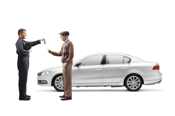 白い背景に隔離された高齢者の男性に車のキーを与える制服で整備士の完全な長さのプロフィールショット — ストック写真