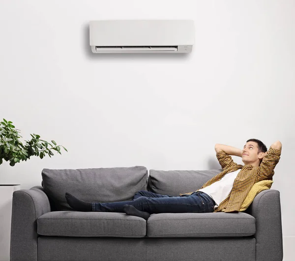 Muž Ležící Pohovce Klimatizací Zdi Doma — Stock fotografie
